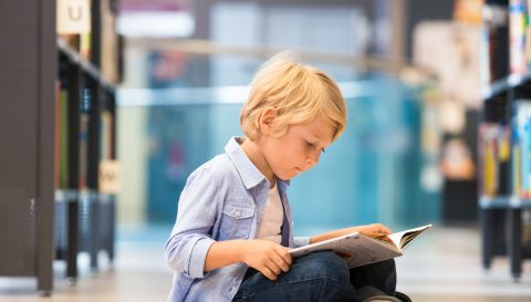 Adorable Little Boy Sitting In Library