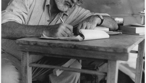 Ernest_Hemingway_Writing_at_Campsite_in_Kenya_-_NARA_-U.S. National Archives and Records Administration