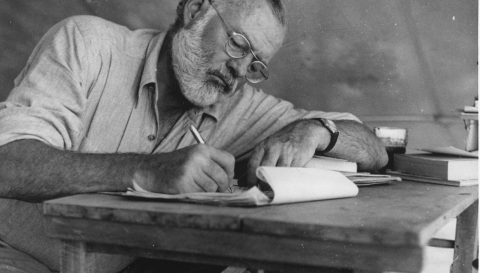 Ernest_Hemingway_Writing_at_Campsite_in_Kenya_-_NARA_-U.S. National Archives and Records Administration