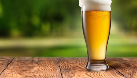 Beer,In,Glass,On,Wooden,Table,With,Blurred,City,Park