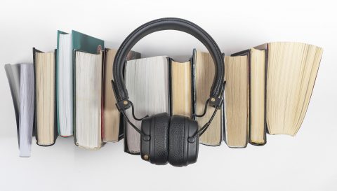 Audio books stack with headphones, top view. Audiobook reading concept
